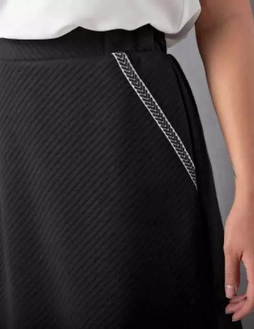 Ozdobné biele prešívanie vreciek na čiernej sukni